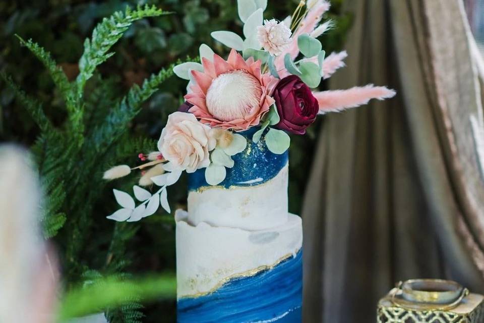Wedding cake with navy and gold detailing and a floral topper