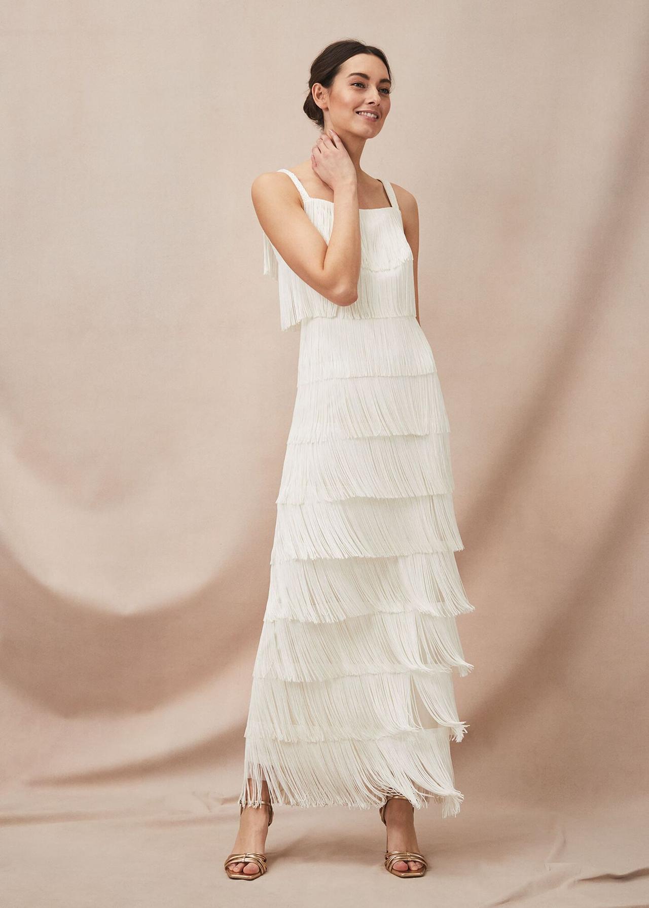 White woman with dark hair in a low chignon wearing a tiered beaded 1920s style wedding dress with a square neckline