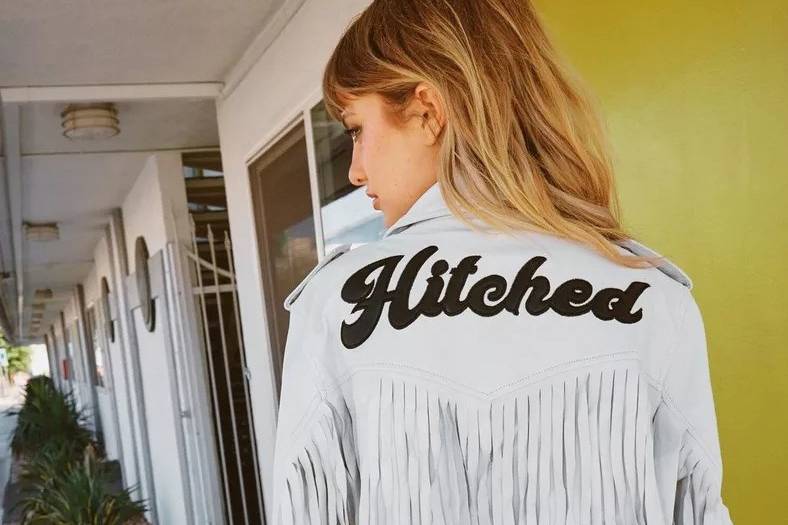 Model wearing a fringe leather jacket with 'hitched' slogan