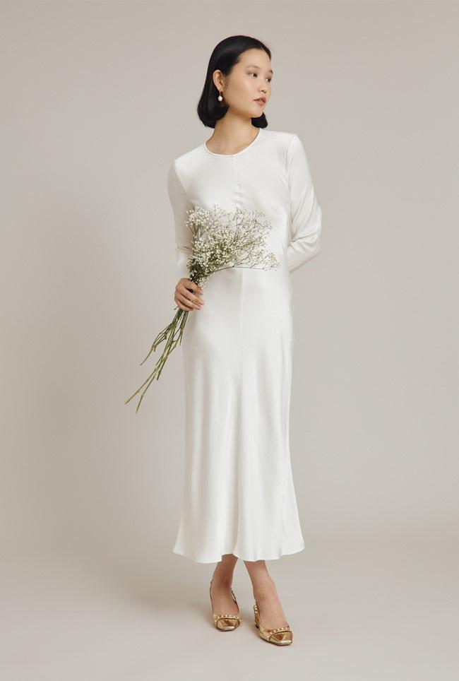 Bride carrying a gypsophila bouquet and wearing a long sleeved midi satin dress
