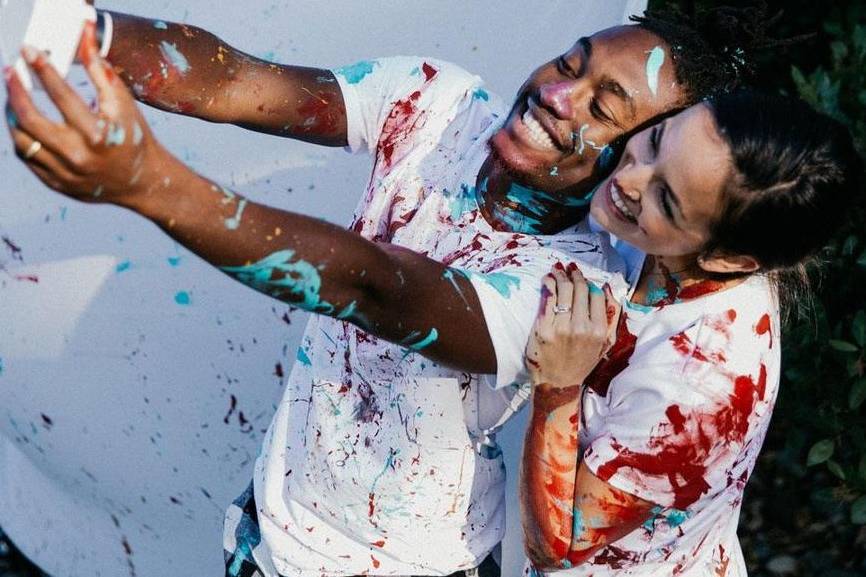 Paint covered couple taking a photo during a gift experience