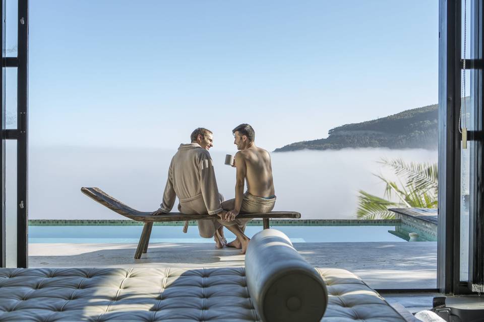 Couple sit on a deckchair with a sea view drinking coffee