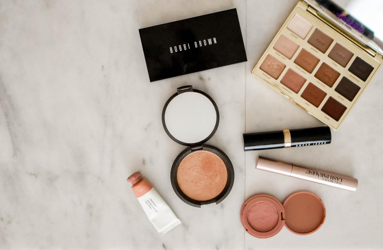 Wedding makeup flatlay featuring products like blusher, eyeshadow palette and lipstick