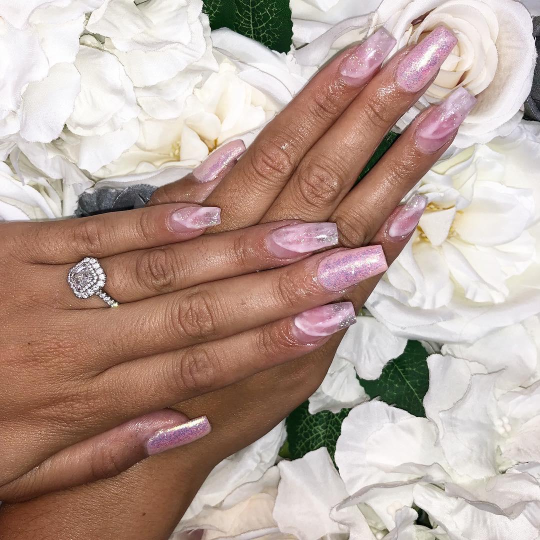 Cara Delahoyde shows off her gorgeous double-halo engagement ring with sparkly pink nails in front of a rose bouquet