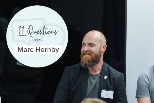 Business owner Marc Hornby sitting by a sign with his name on it