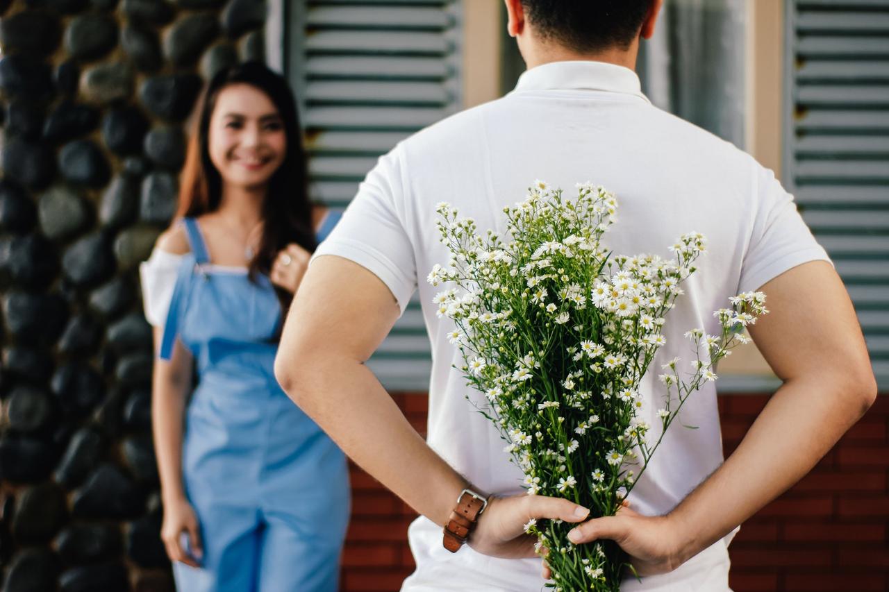 man suprising woman with flowers