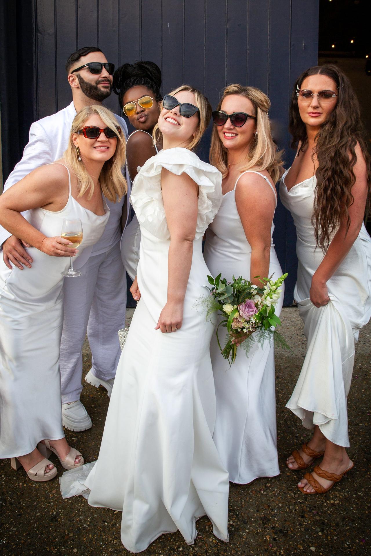 The bride, her bridesmaids and bridesman pose in sunglasses