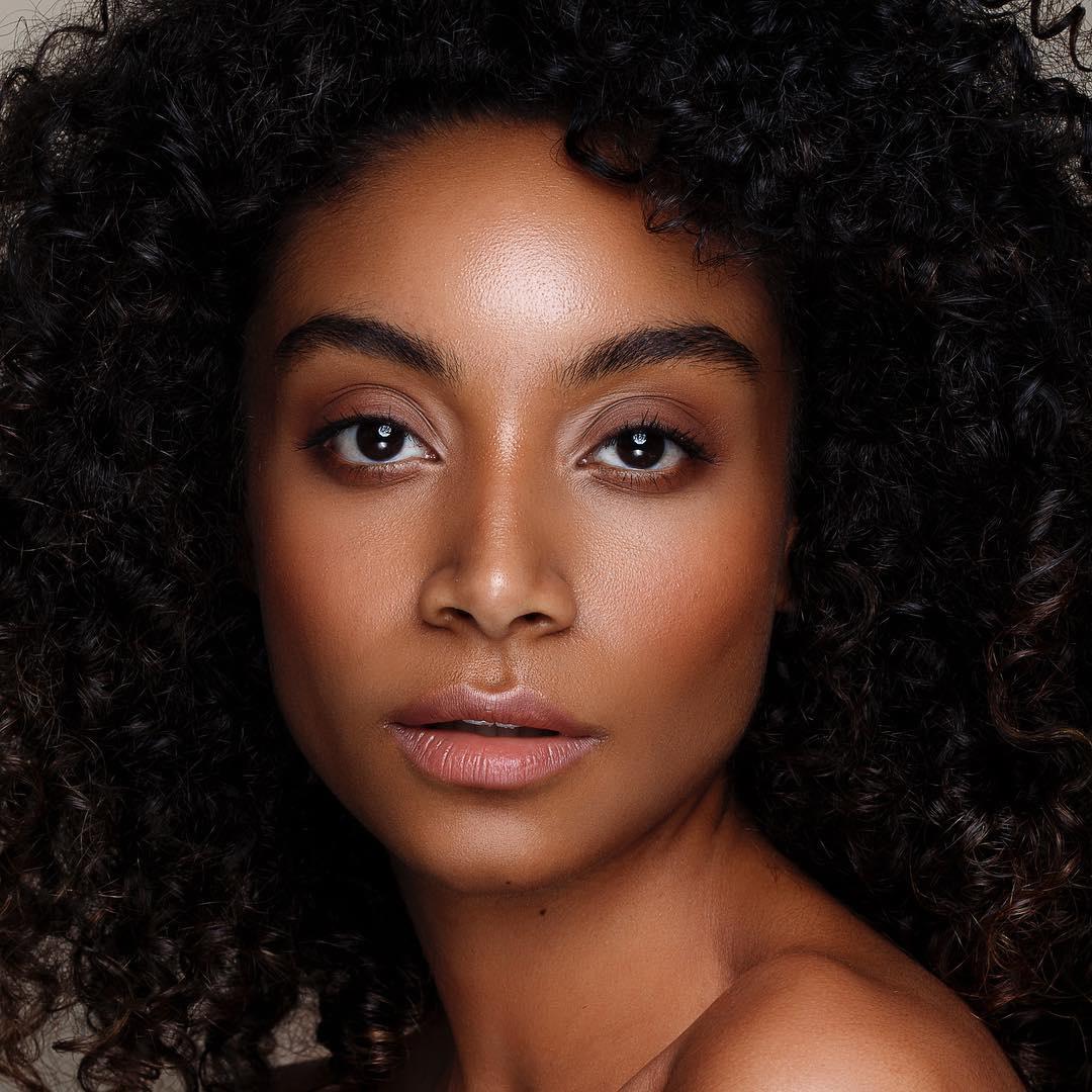 Model with afro hair and sculpted makeup with a nude lip