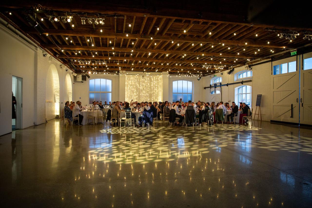 Guests enjoy the wedding breakfast under a canopy of fairy lights