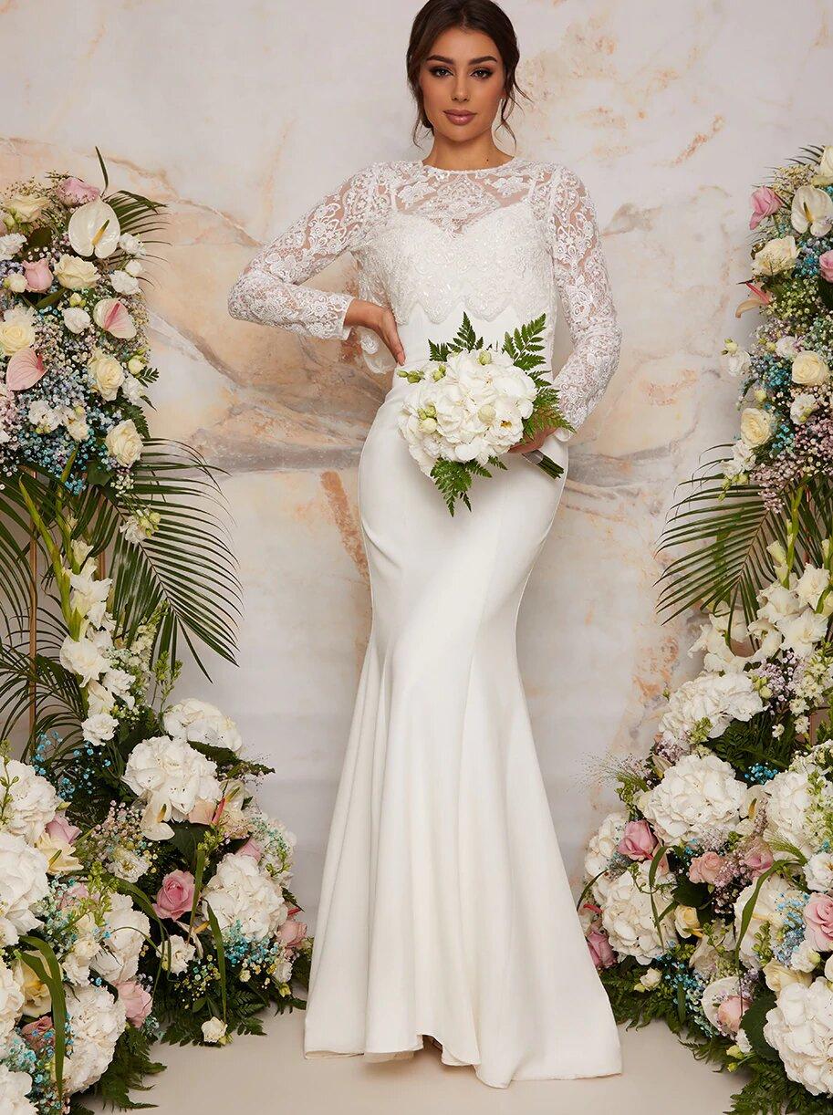 Model wearing a lace long sleeved top and skirt wedding dress