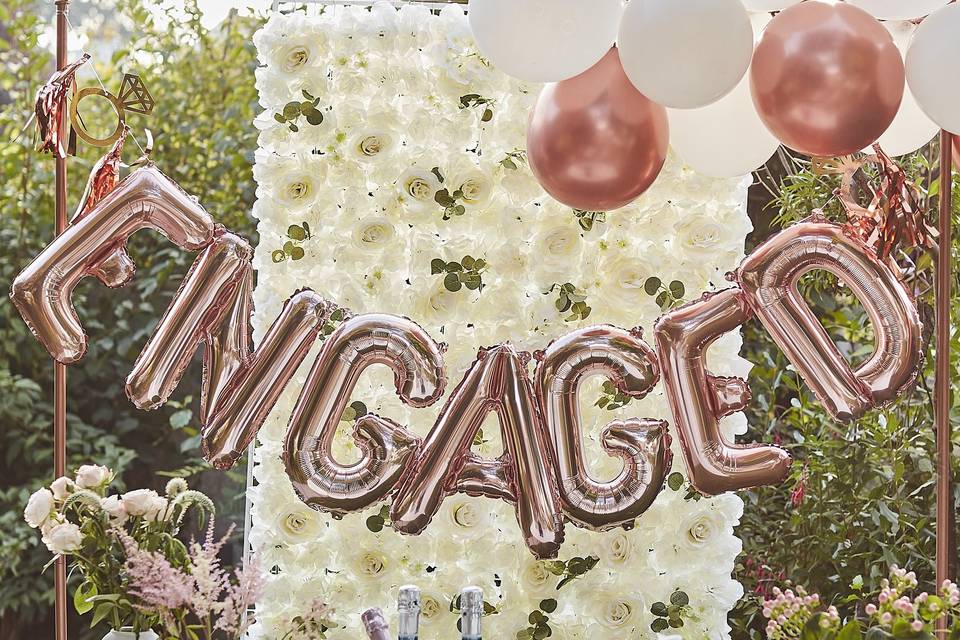 Engagement party decorations with a white flower wall and rose gold balloons 