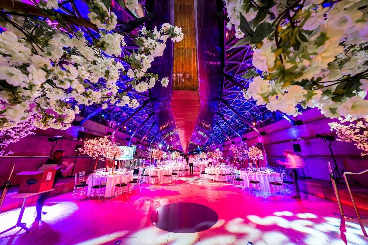 huge wedding reception room with pink LED lighting and tables and chairs set up for a party