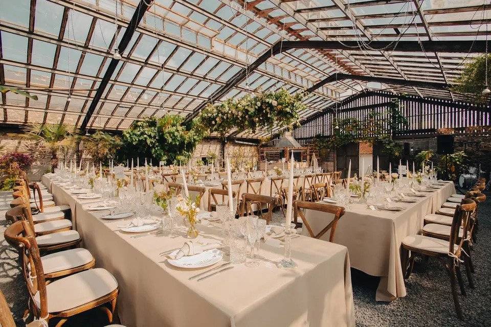 Glass room set for wedding breakfast with dinner candles, loral arrangements and wooden chairs