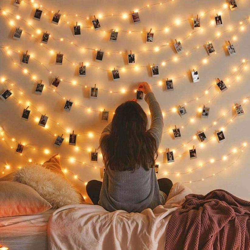 Girl hanging up photos with fairy light clips