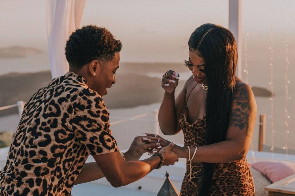 A man putting a ring on his girlfriend's finger after he proposed and she said yes in Santorini