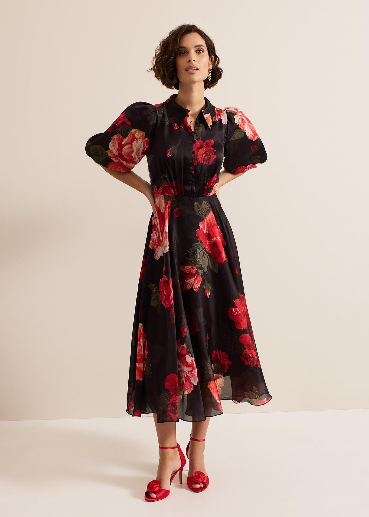 A wedding guest wearing a black and red floral print shirt midi dress with puff sleeves. She is wearing it with red satin heels.