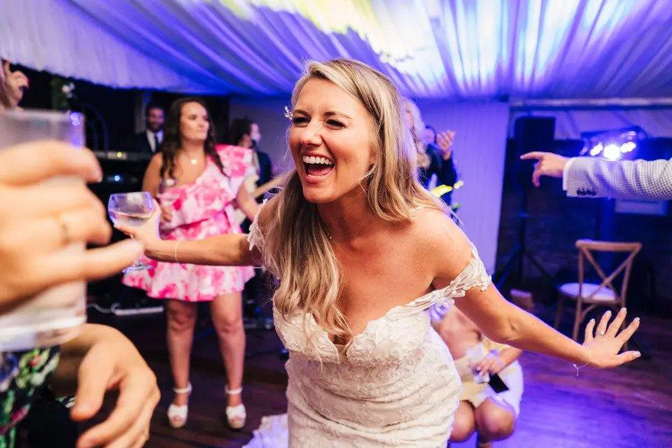 Bride beaming as she dances on the dancefloor at her wedding