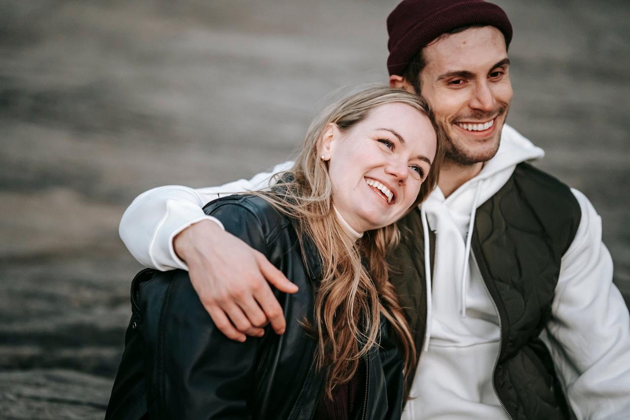 smiling man with his arm around woman smiling