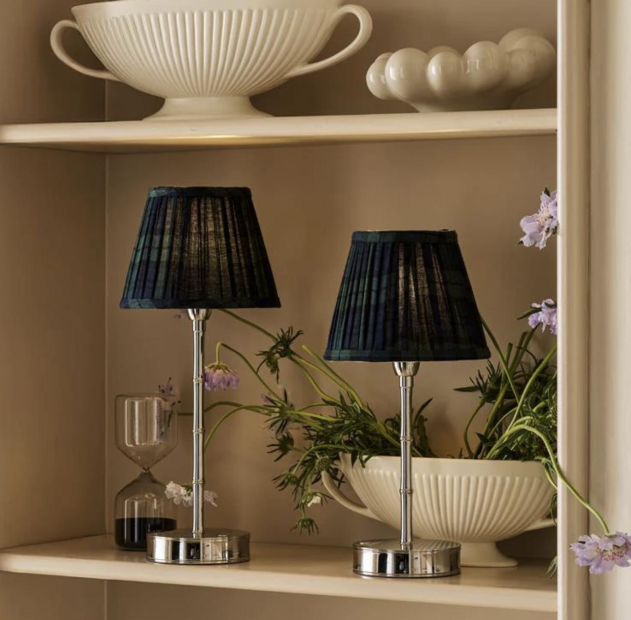 two large and small dark green and navy tartan cotton lampshades on a cream shelf