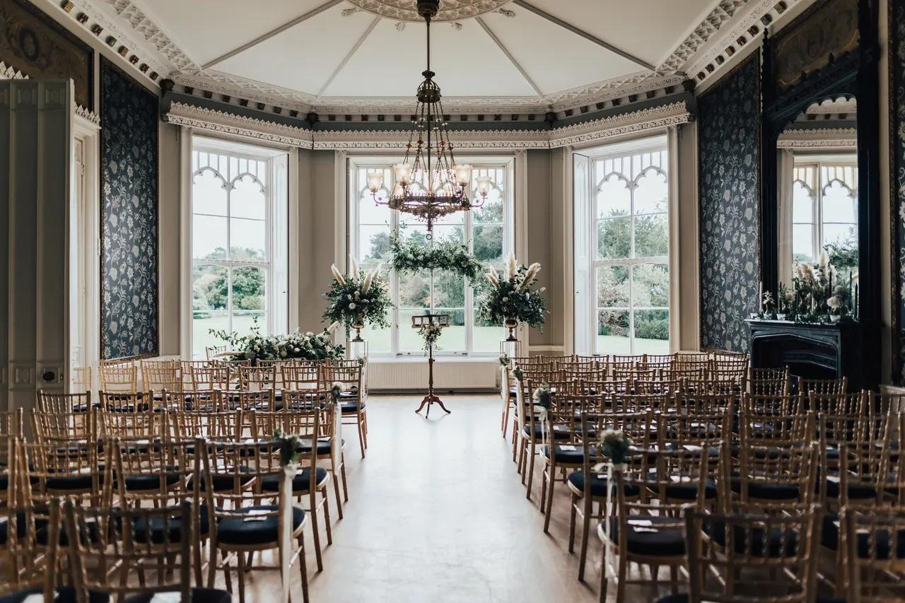 A regal suite set up for a wedding ceremony with an modern irregular wedding arch