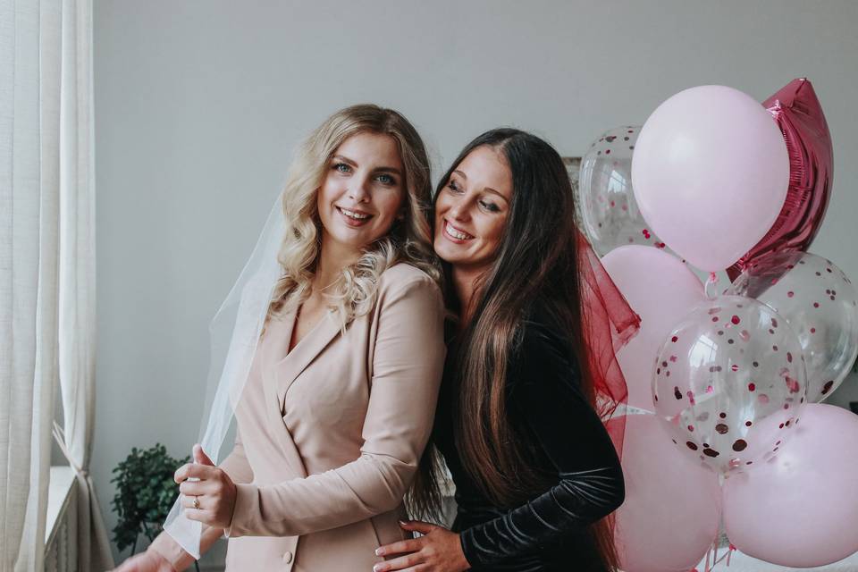 Bride-to-be with her best friend at her hen party in front of a backdrop of balloons