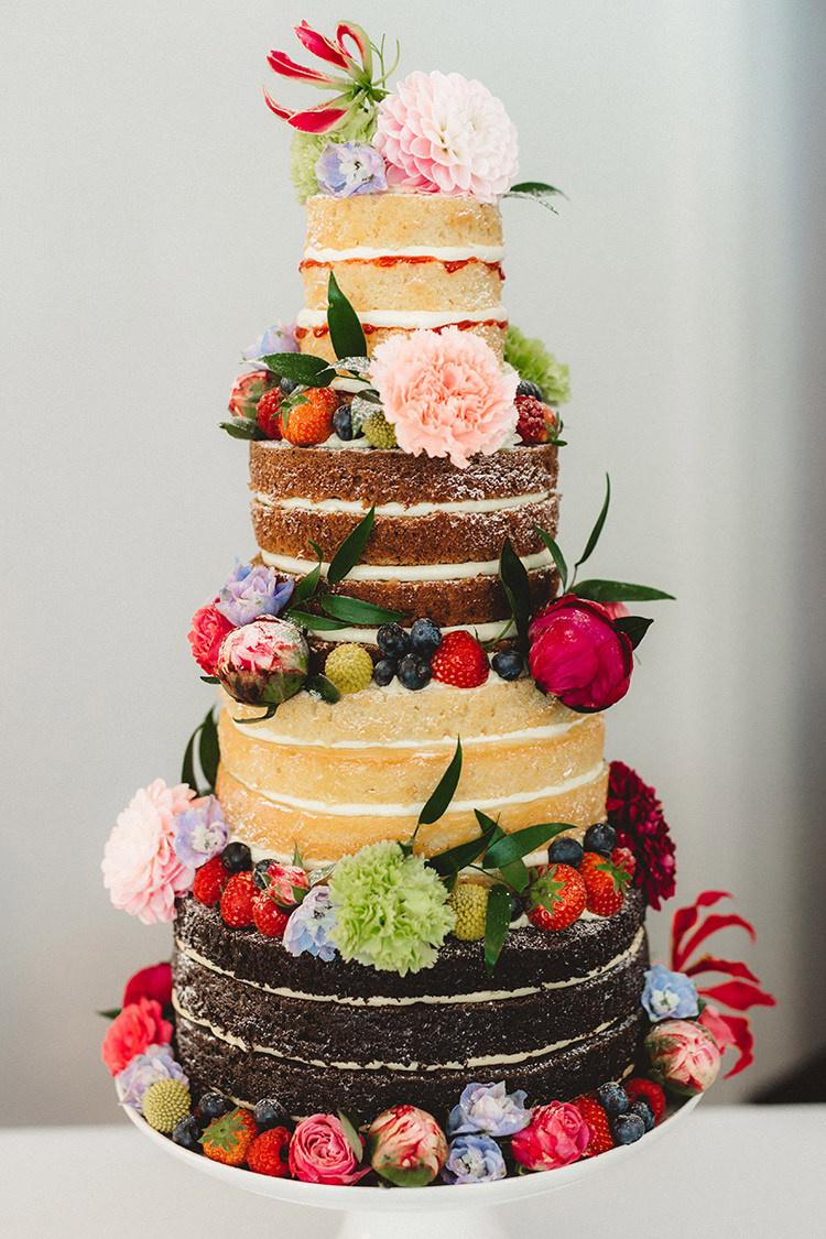 Four layered multi-flavour rustic wedding cake with flowers and fruit