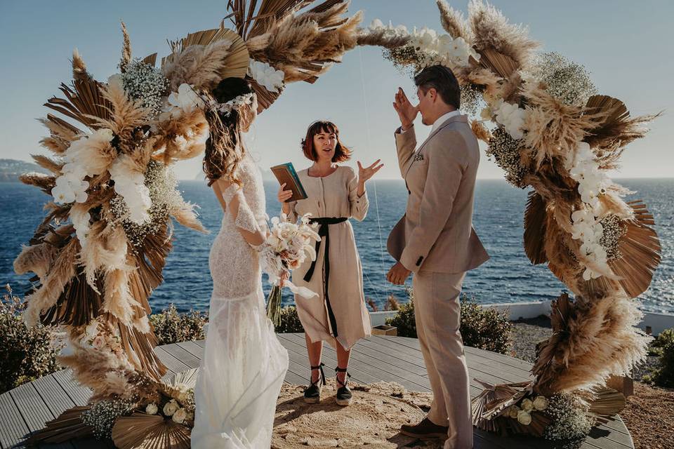 Couple standing at the altar at their Ibiza wedding in front of a round floral arch