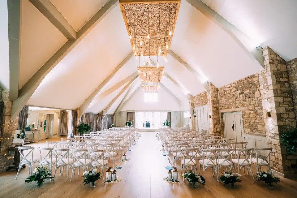 Light and airy ceremony room at the frogmill set up for wedding with exposed bulbs, chairs and flowers