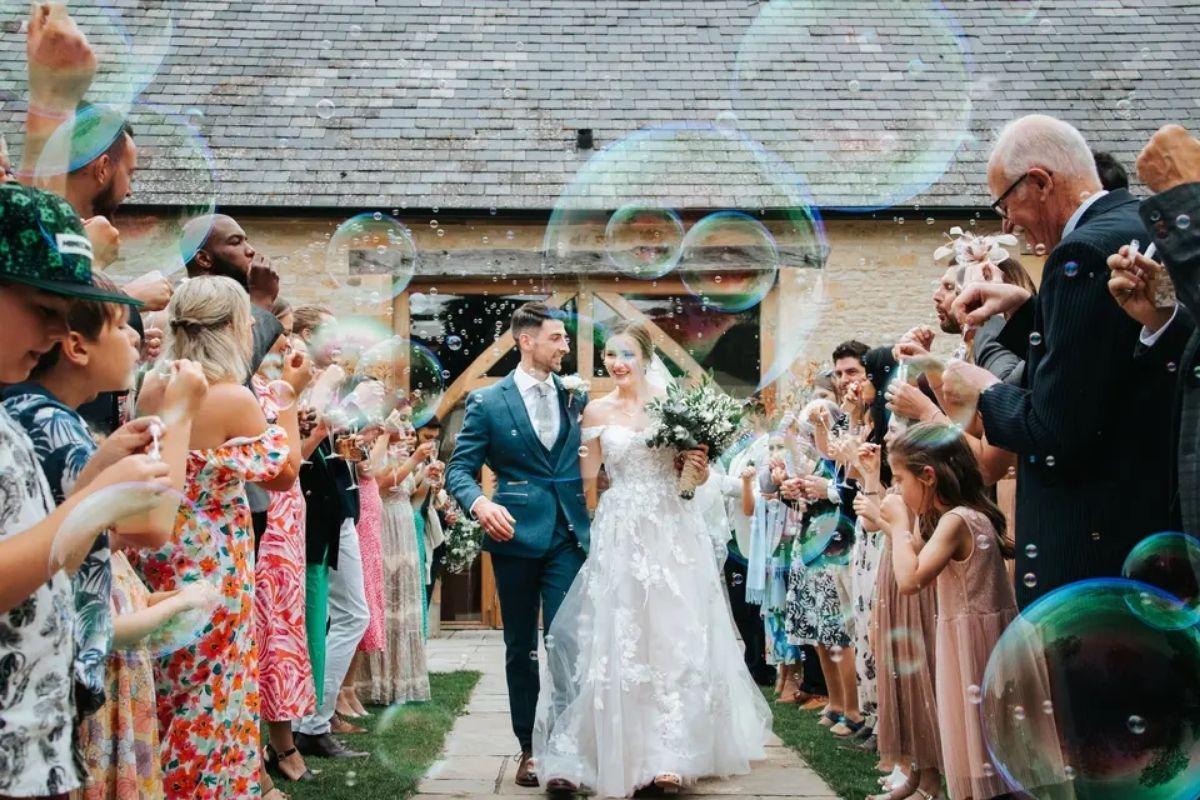 a fun shot showing a bride and groom exiting their wedding ceremony with guests blowing bubbles