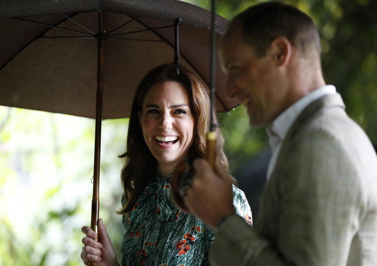 Kate Middleton and Prince William laugh in the rain under umbrellas
