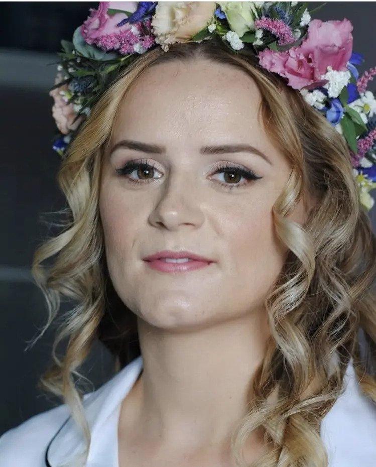 Portrait of a bride with winged eyeliner and a floral headpiece looking directly at the camera