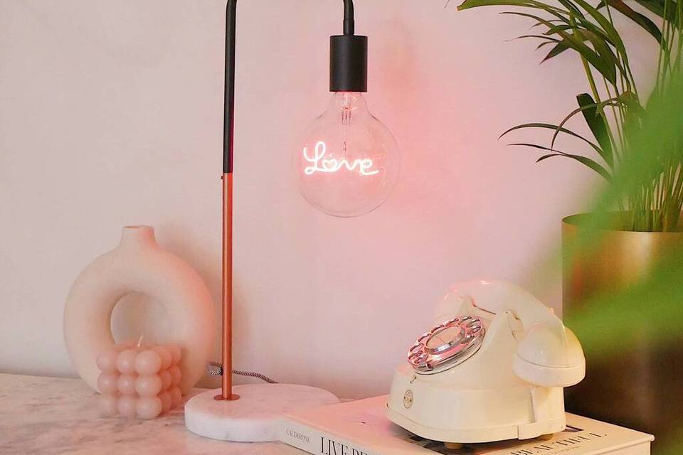 A contemporary bulb lamp with LED words inside that read 'Love'