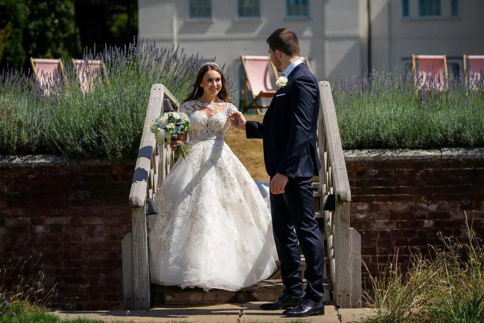groom extends helping hand to bride walking down stairs outside a wedding venue