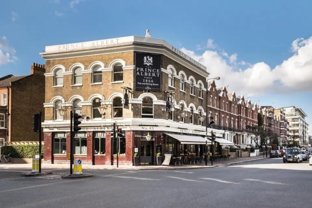  the prince albert pub on a london corner with chairs set up outside and traffic next to it