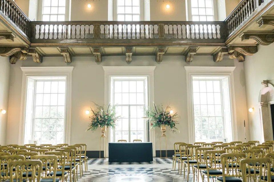Ceremony room with golden chairs, chequered floor, balconies and floral decorations
