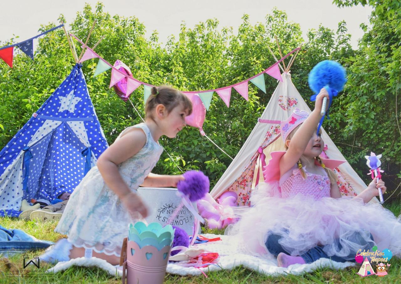 Children dressed as fairies playing outside of teepees 