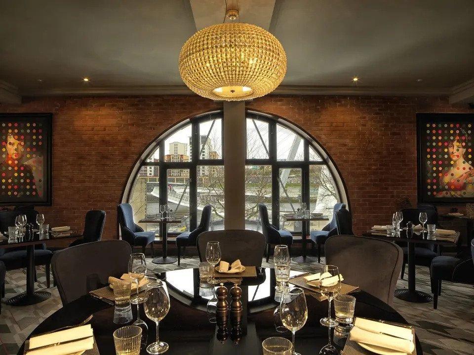 Restaurant at Malmaison with laid tables, chandelier and view out the window