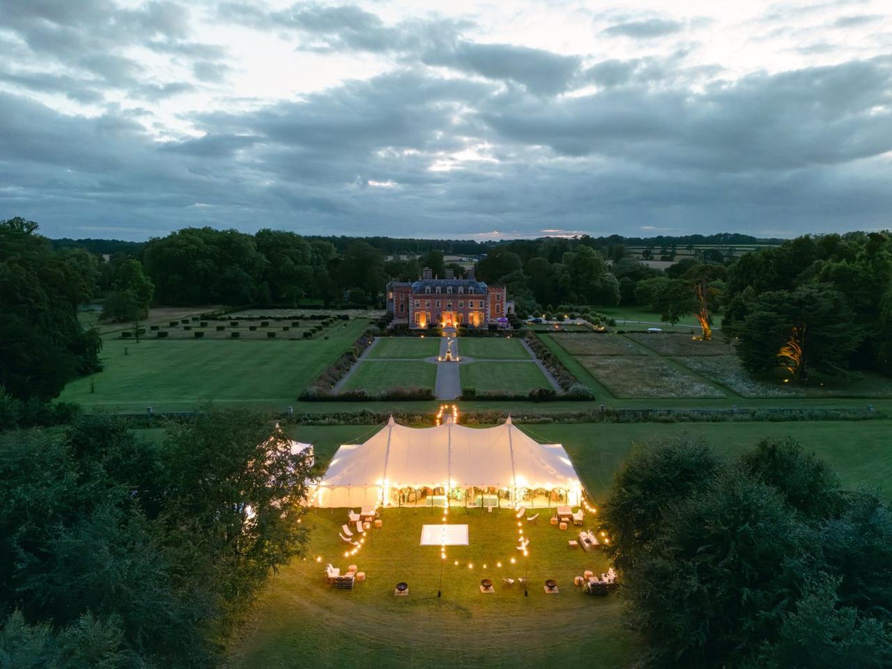 Aerial view of St Giles House marquee at end of garden with fairy lights at dusk, Dorset 