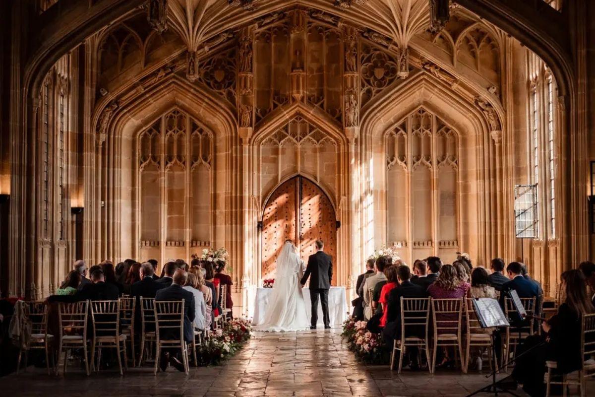 a central shot showcasing a romantic wedding ceremony in a detailed chapen with guests seated and the bride and groom standing at the altar