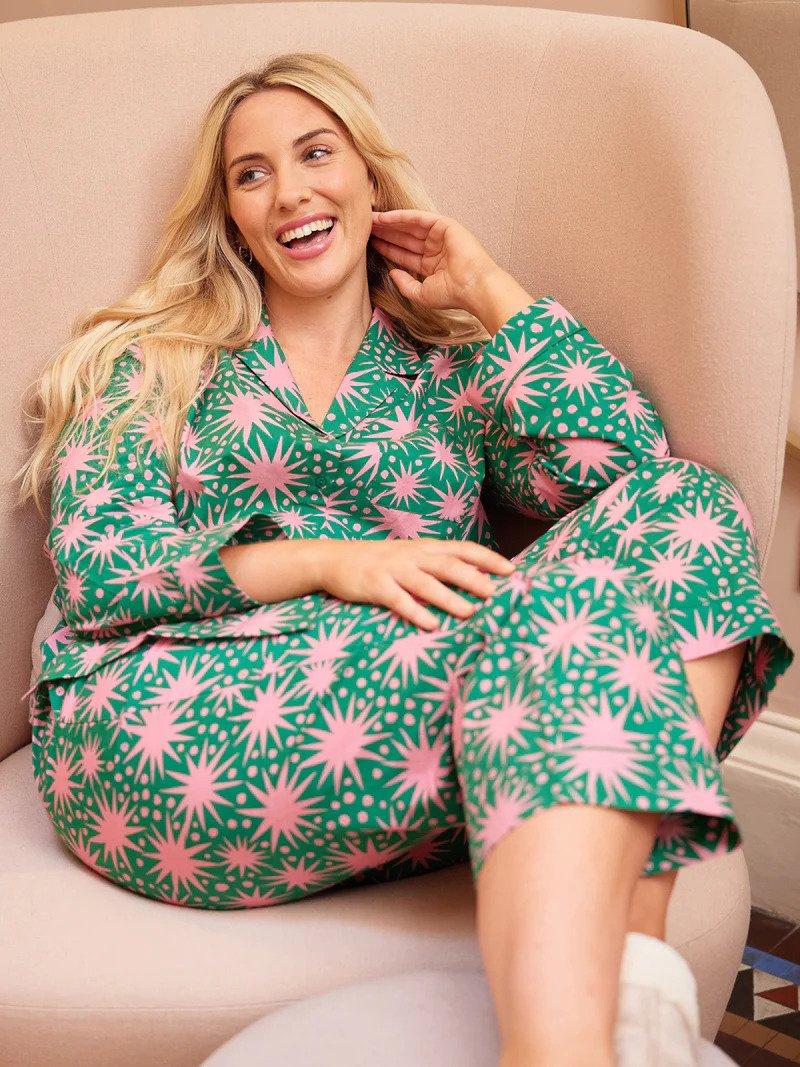 A model sitting back in a chair wearing a pair of green pyjamas with a bold pink star pattern across it