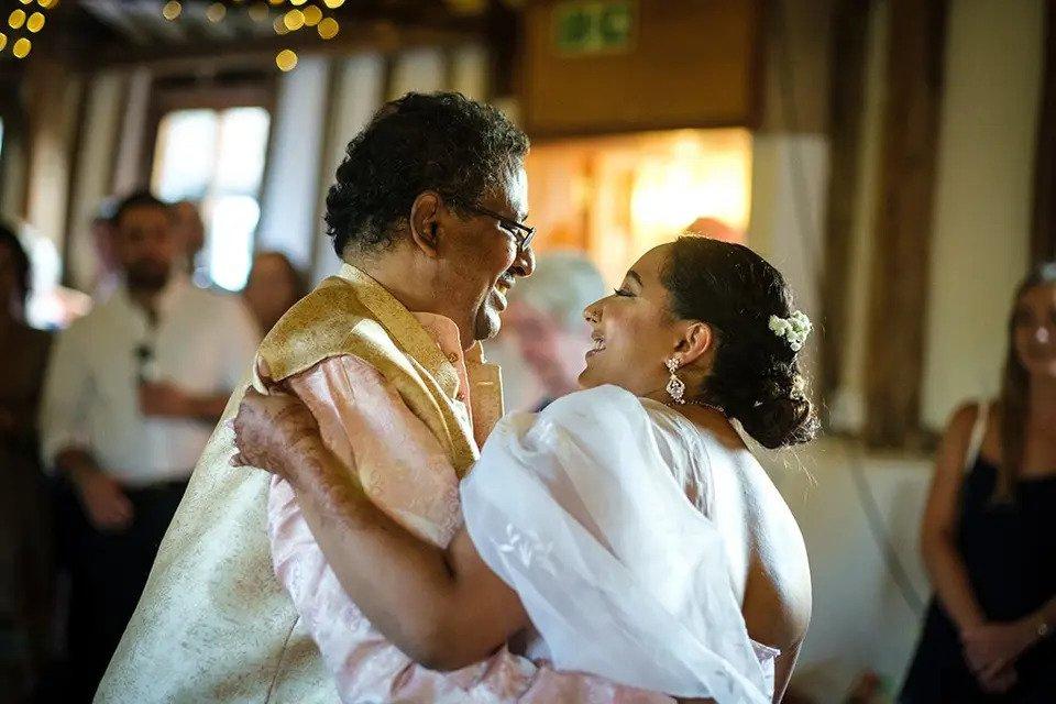 Close up shot of a father-daughter dance with guests watching in the background