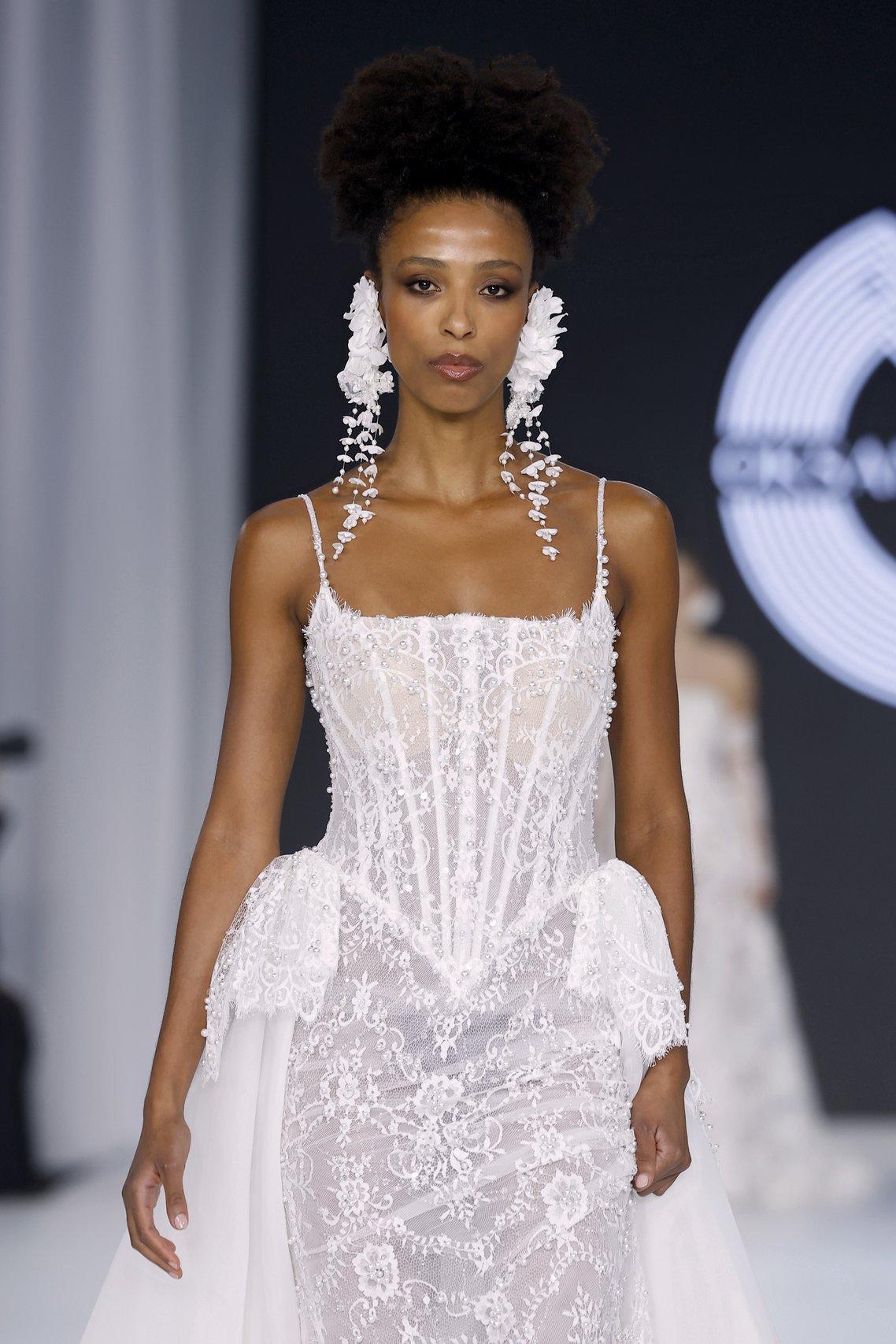 Oksana Mukha at Barcelona Bridal Week 2026, styling oversized floral earrings with embellished wedding dresses