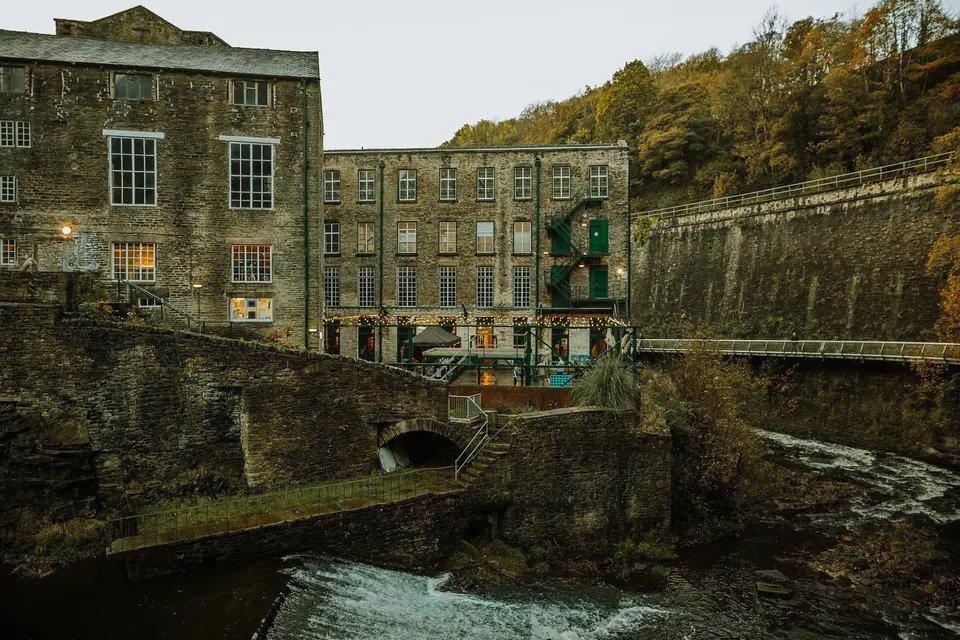 Grey stone exterior of a water mill surrounded by trees