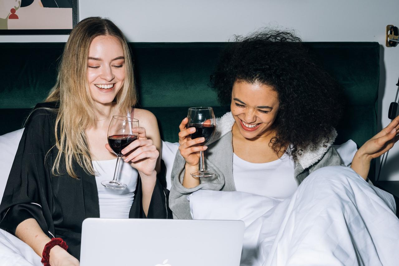 Girls laughing in bed with wine