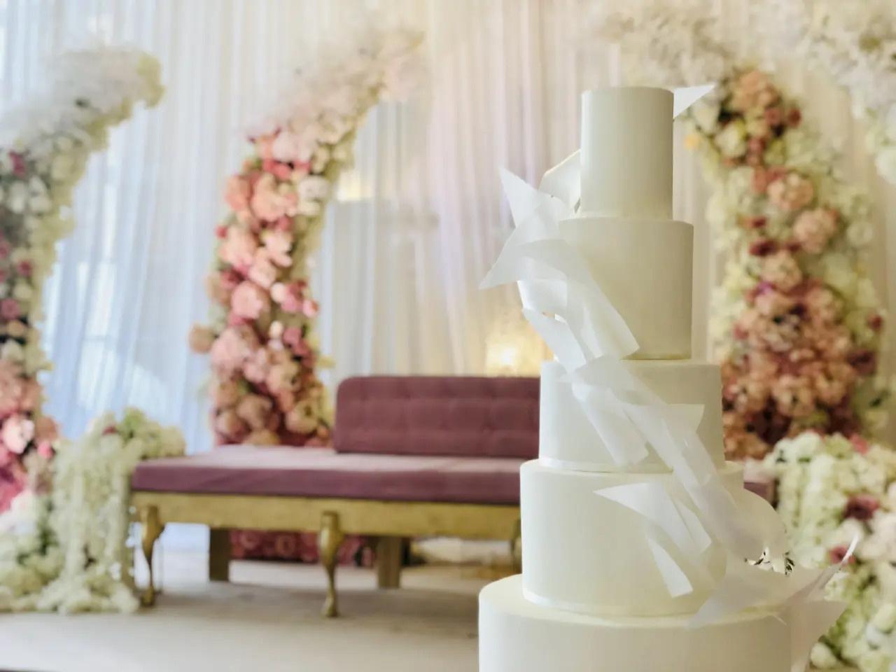 An elegant white wedding cake is set amongst floral decorations