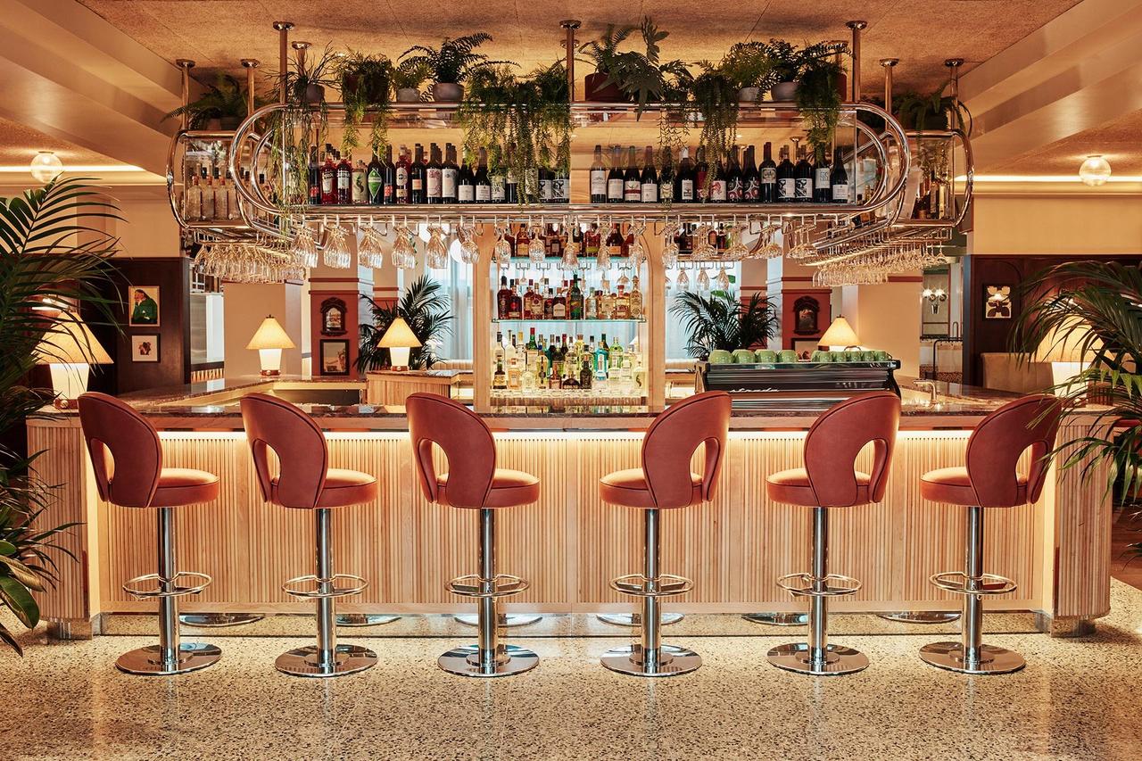 An amber lit modern tropical themed bar with tall chairs and bottles of alcohol