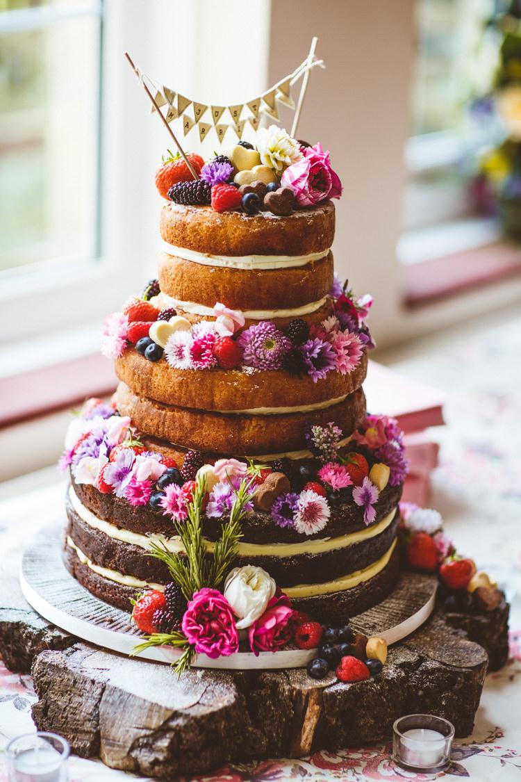 Three tiered victoria sponge rustic wedding cake with flowers, fruit and bunting topper