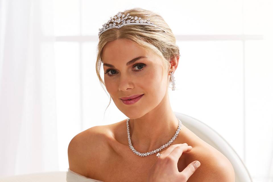 Bride with blonde hair in a bateau neck wedding dress wearing a sparkling tiara, necklace, ring and bracelet