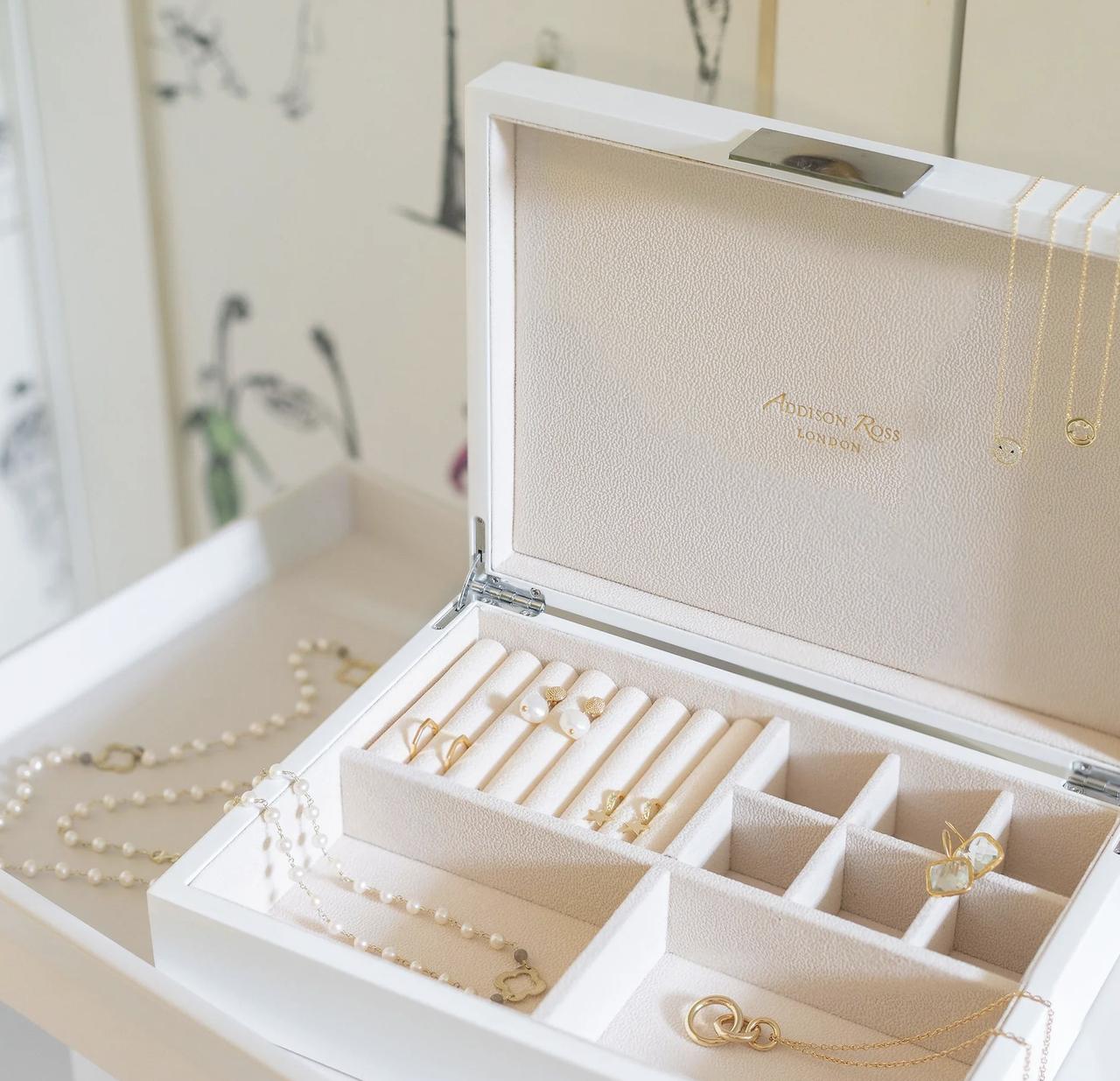 white leather jewellery box filled with gold jewellery on a dressing table
