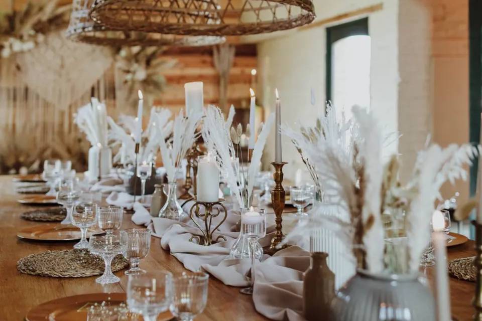 a long wedding breakfast table with a runner and white feathered centerpieces going all the way down